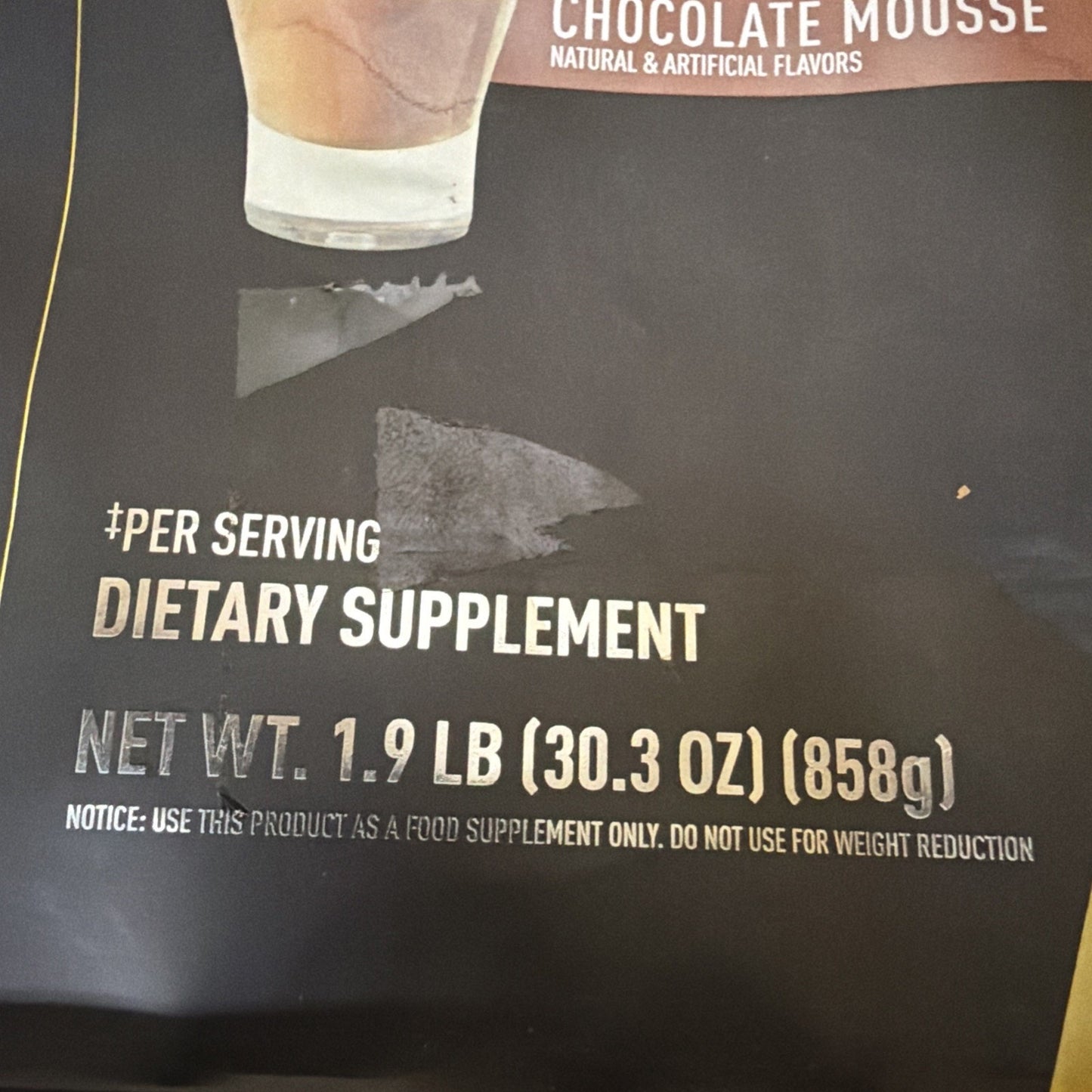 Close-up of a dietary supplement package showing net weight of 1.9 pounds (858 grams) and a notice stating it is for food supplement use only, not for weight reduction.