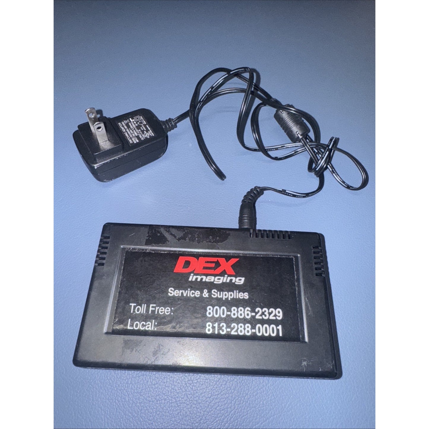 DEX Imaging Print Counter device with power adapter and service contact information on label