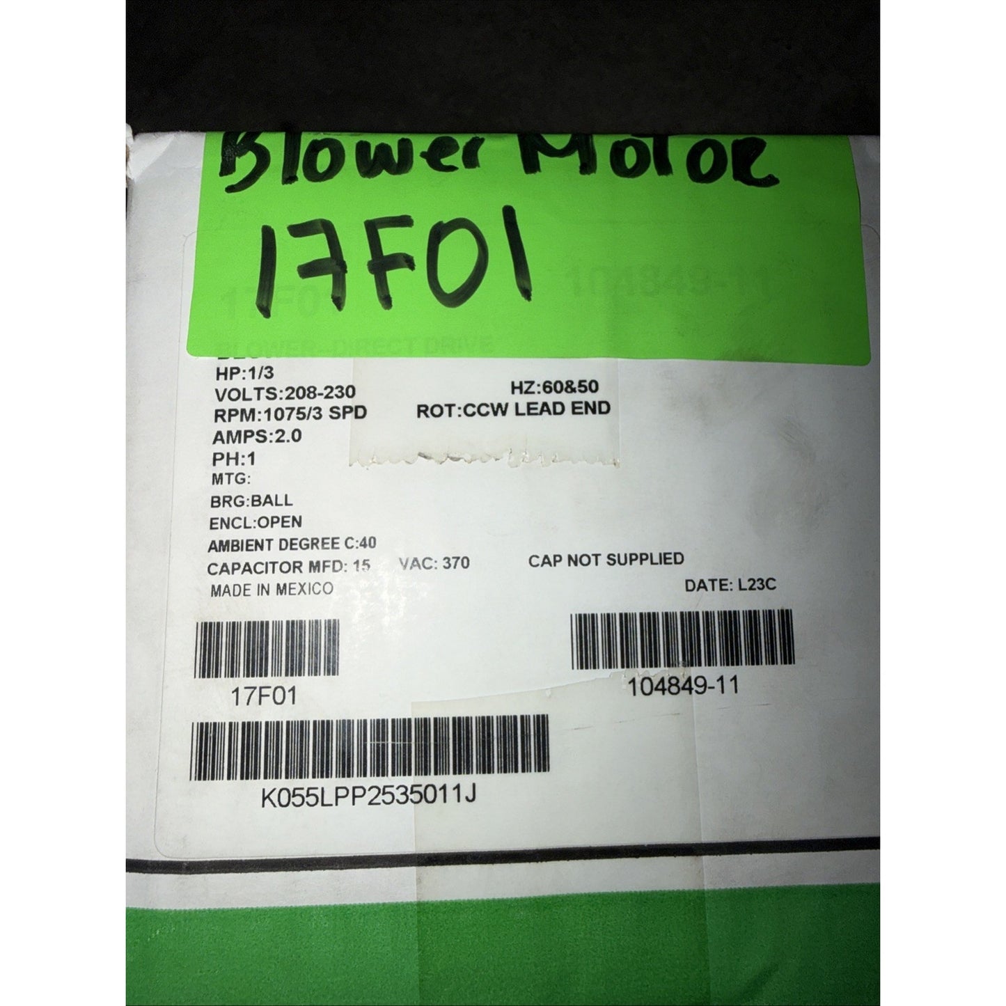 White product label with black text detailing electrical specifications including voltage, RPM, amps, capacitor ratings, manufacturing origin, barcodes, and the handwritten note "Blower Motor 17F01" on a green background.