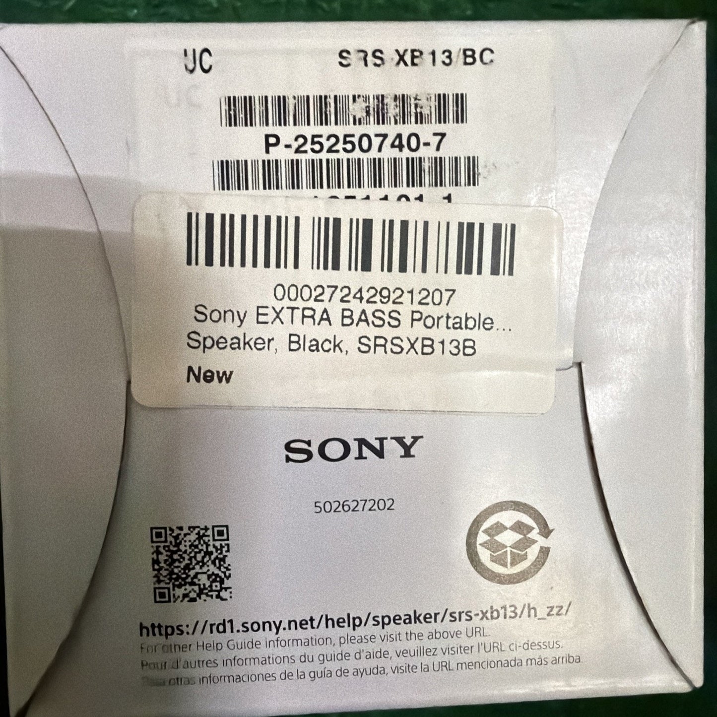 Close-up of a white product box label showing barcodes, a QR code, and text indicating a Sony Extra Bass portable black speaker model SRSXB13B with a website URL for support information.
