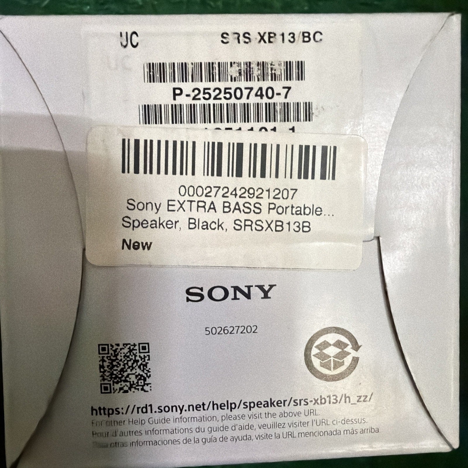 Close-up of a white product box label showing barcodes, a QR code, and text indicating a Sony Extra Bass portable black speaker model SRSXB13B with a website URL for support information.