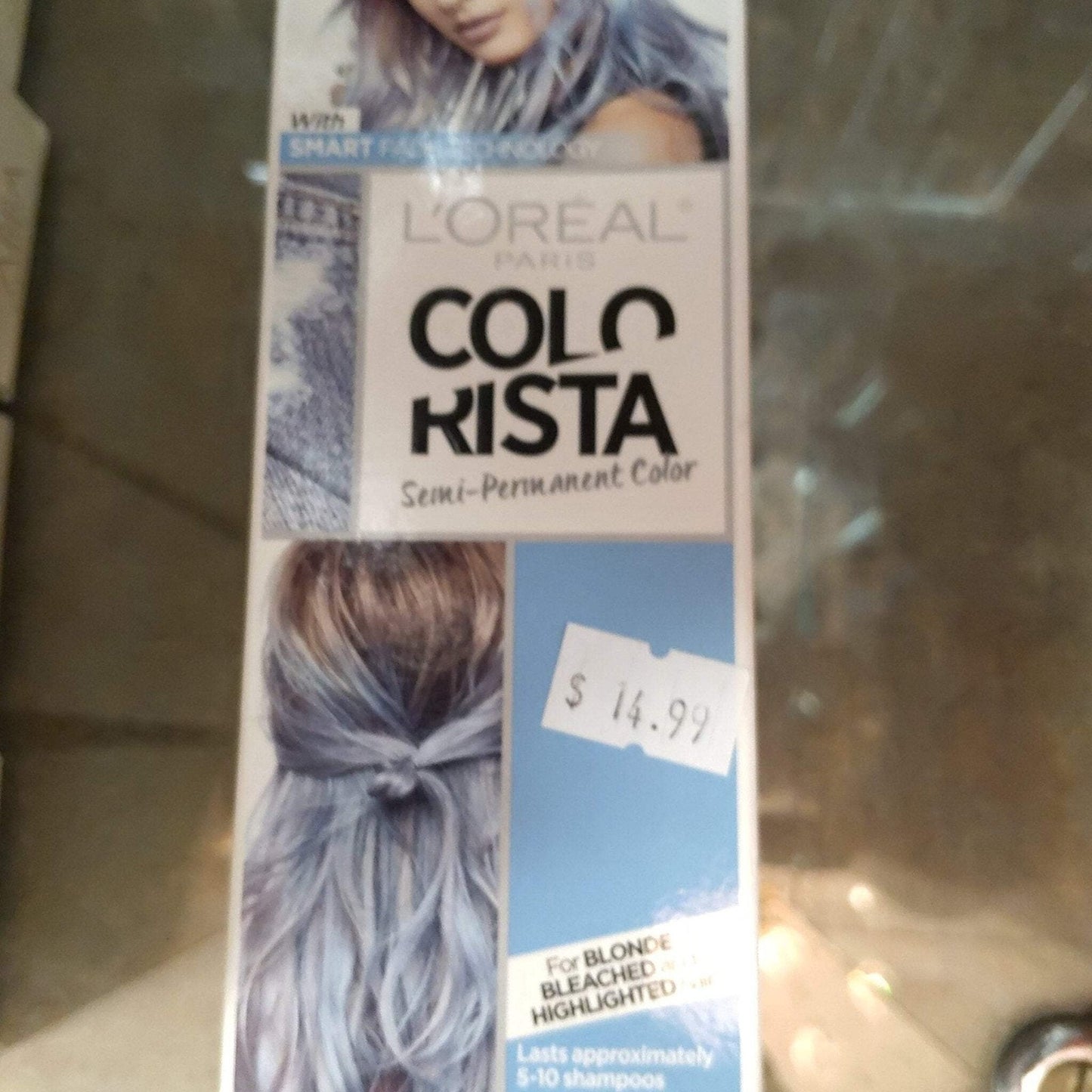 Box packaging of L’Oréal Paris Colorista semi-permanent hair dye in a blue shade, featuring images of light blonde hair with blue highlights and a price sticker showing $14.99.