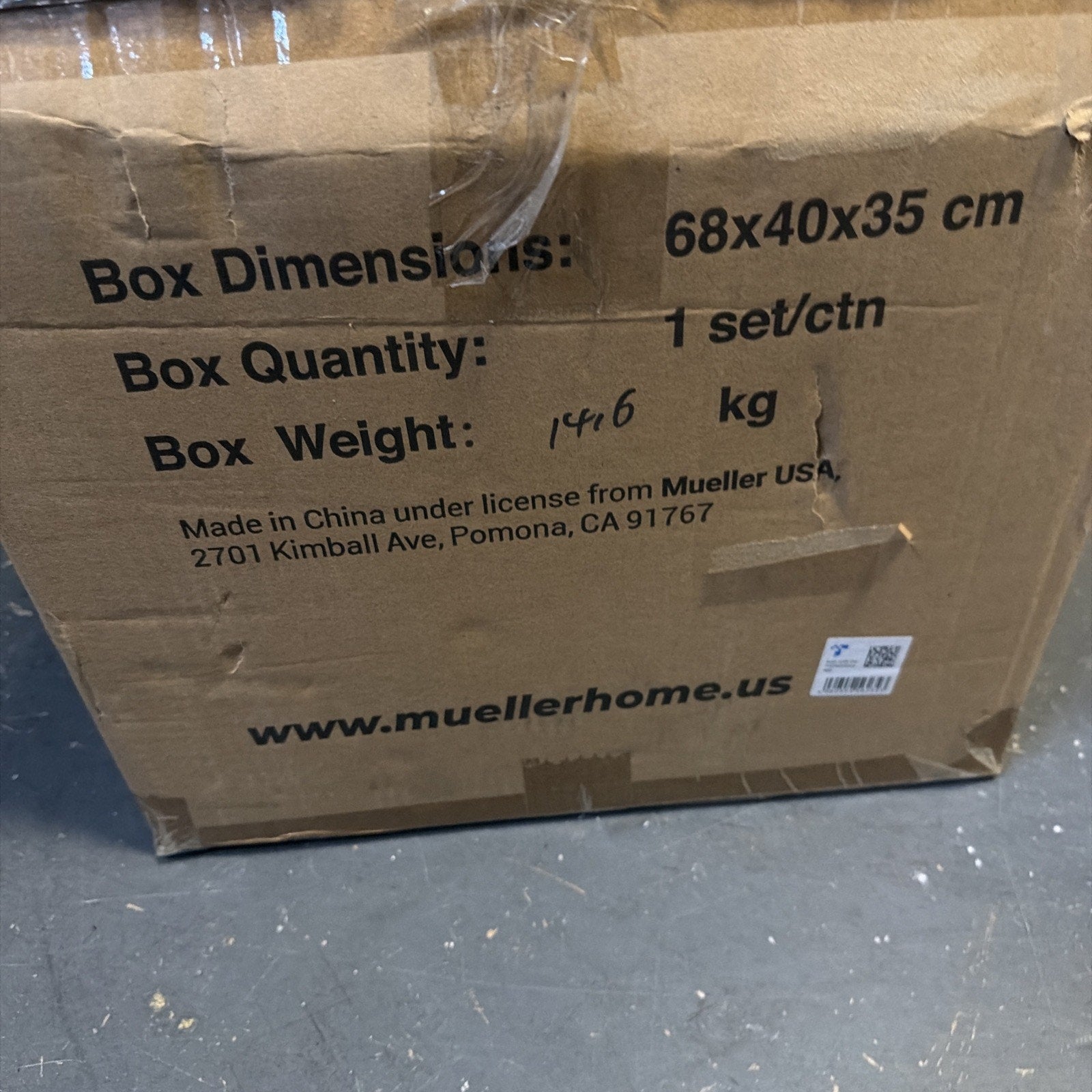 Close-up of a cardboard shipping box with printed dimensions 68x40x35 cm, quantity of 1 set per carton, handwritten box weight of 14.6 kg, and manufacturer information including a website URL.