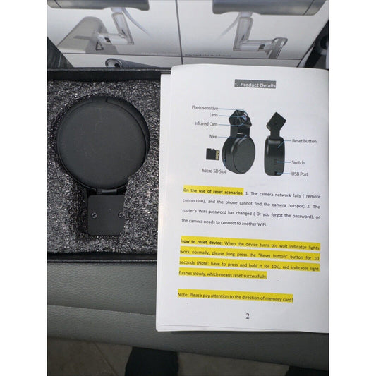 Compact black camera with lens cap and user manual showing reset instructions and product details in foam packaging
