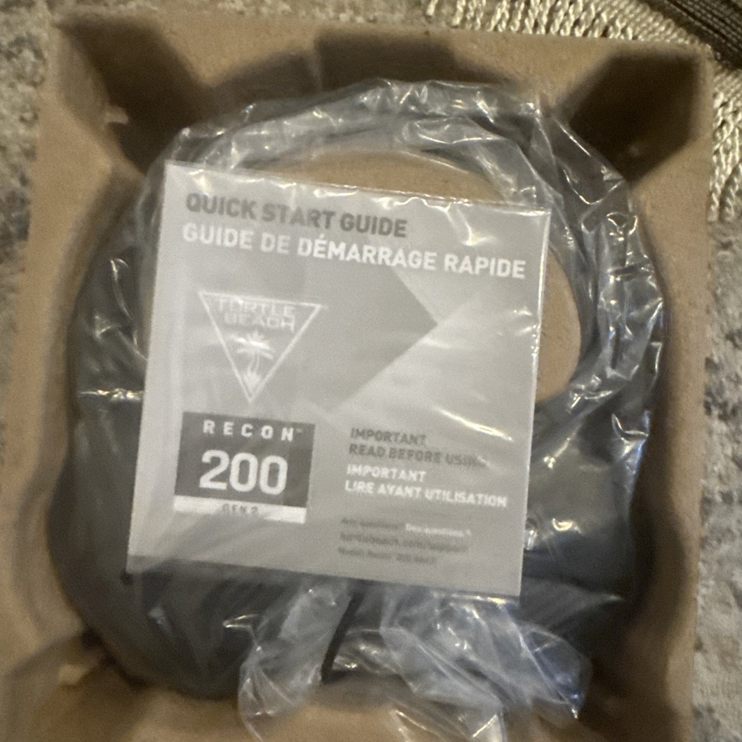 Quick start guide for Recon 200 headset placed on top of a black coiled cable, both inside molded cardboard packaging.