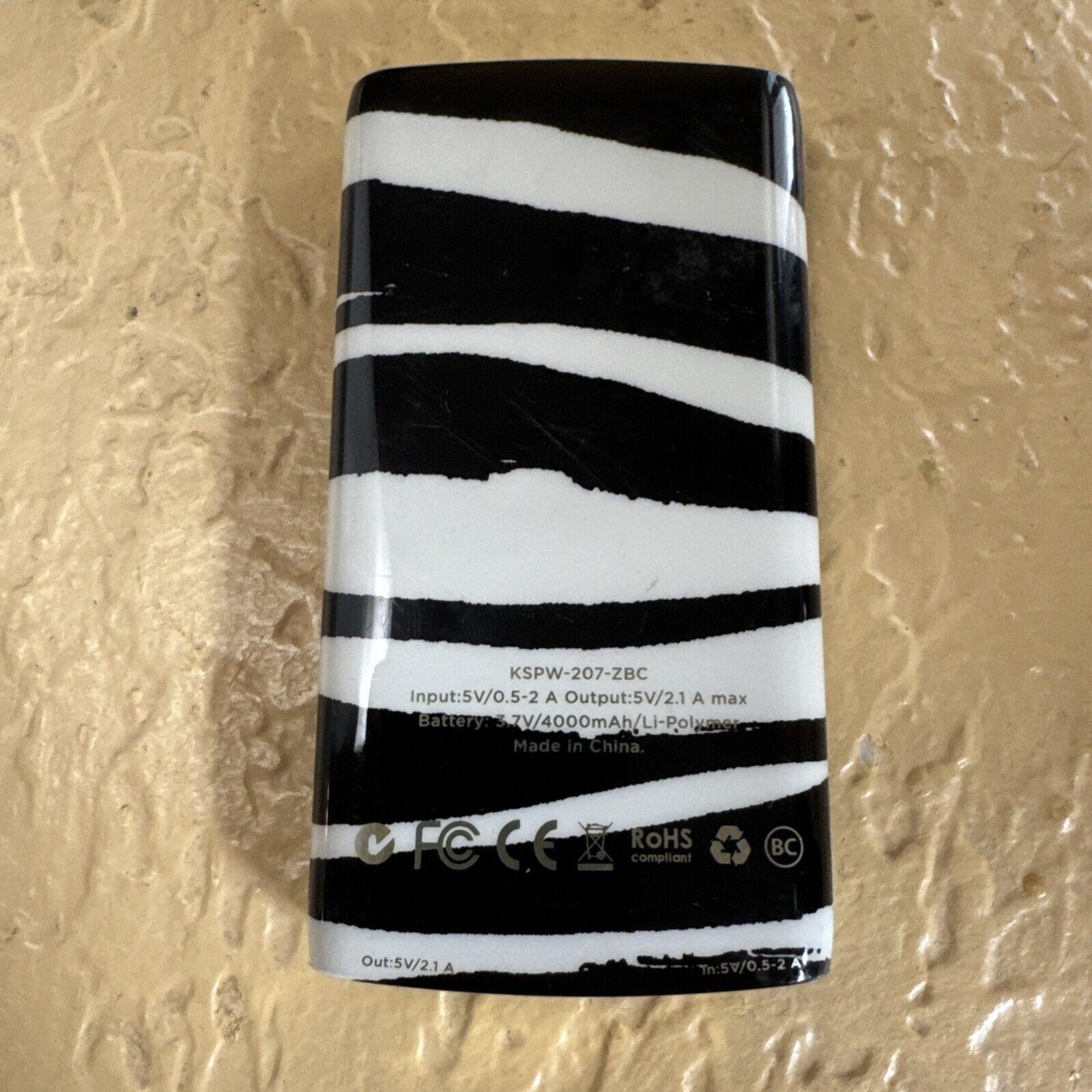 Kate Spade New York 4000mAh backup battery bank with black and white striped design on textured surface