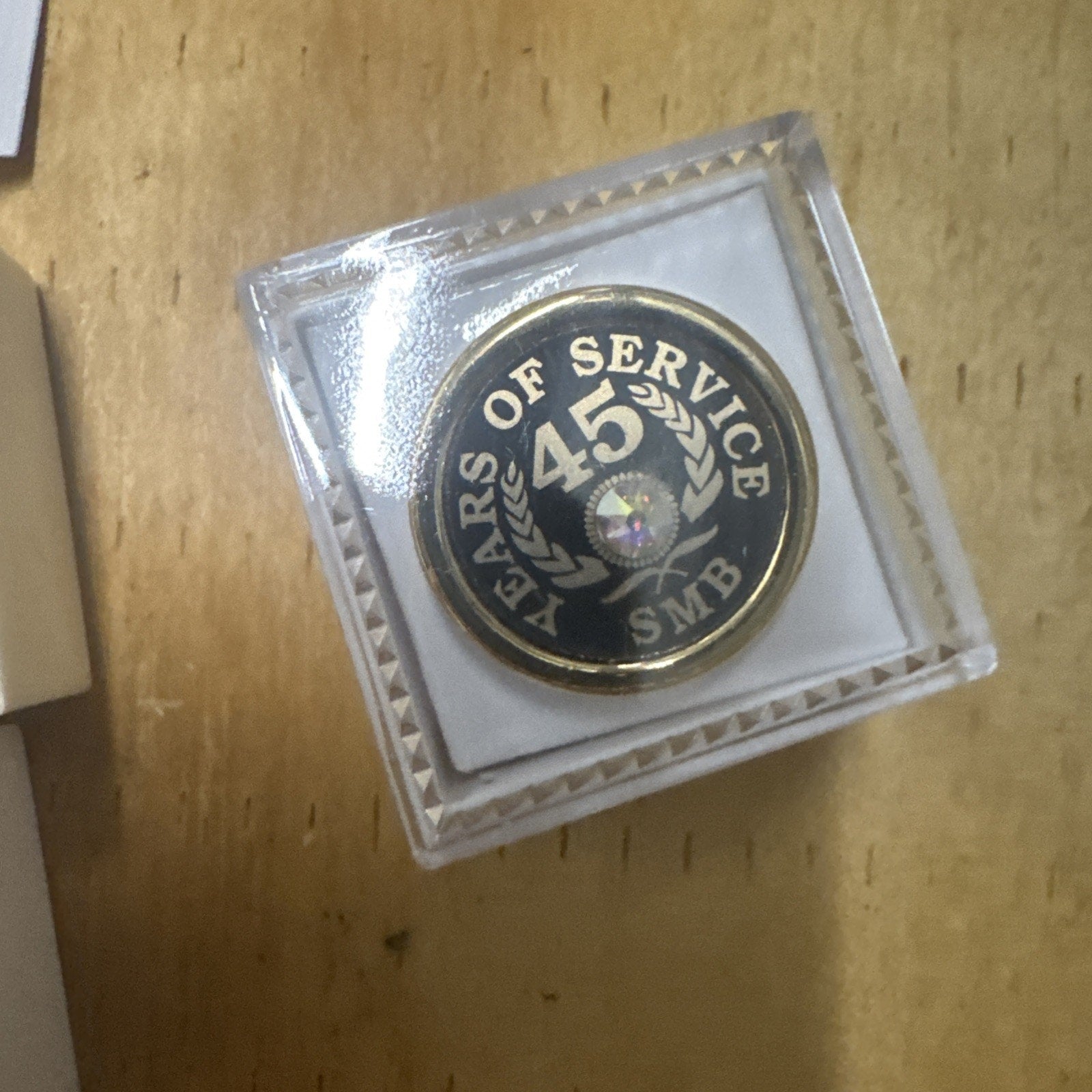 45 Year gold tone employee award pin with laurel wreath and SMB logo in clear display case