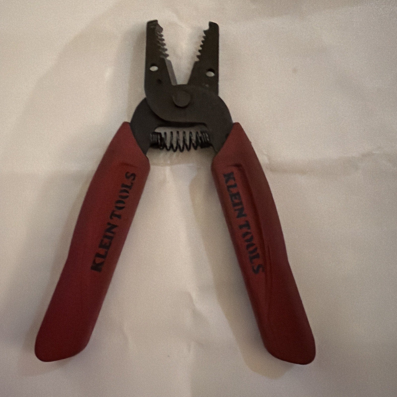 Klein Tools 11046 wire stripper and cutter pliers with red handles and black metal cutting jaws on white background