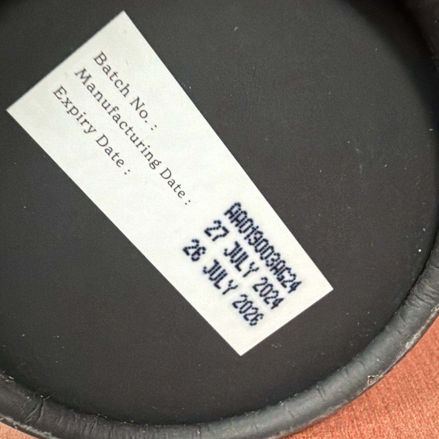 Close-up of a white label on a dark surface showing batch number ARD03092424, manufacturing date of 27 July 2024, and an expiration date of 26 July 2028.