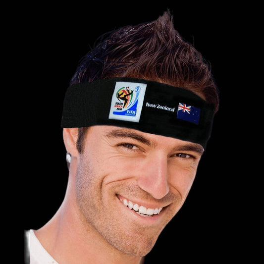 Smiling man wearing a black headband featuring the 2010 FIFA World Cup South Africa logo, the word "New Zealand," and the New Zealand flag against a black background.