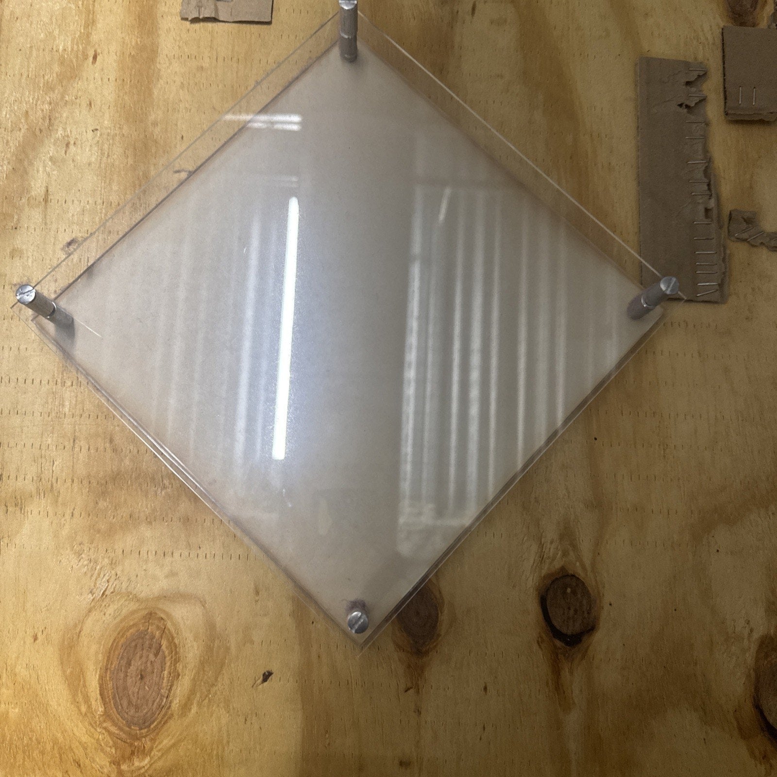 Wella Framed Photo Display showing clear acrylic frame mounted with screws on wooden surface background