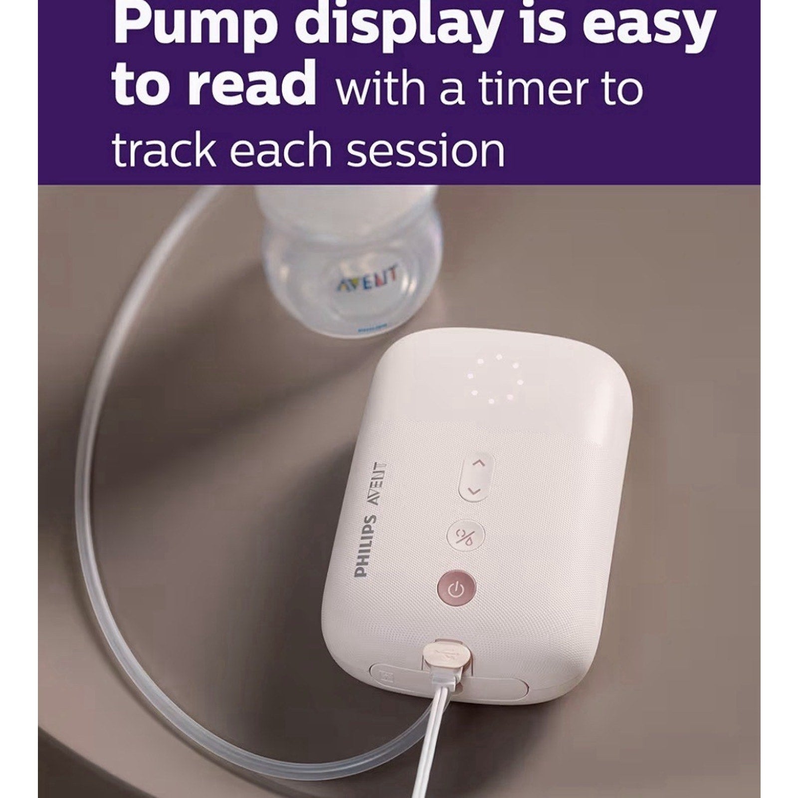 Close-up of a white Philips Avent electric breast pump with a clear tube connected to a bottle, set on a beige surface, featuring illuminated control buttons and text stating the pump display is easy to read with a timer.