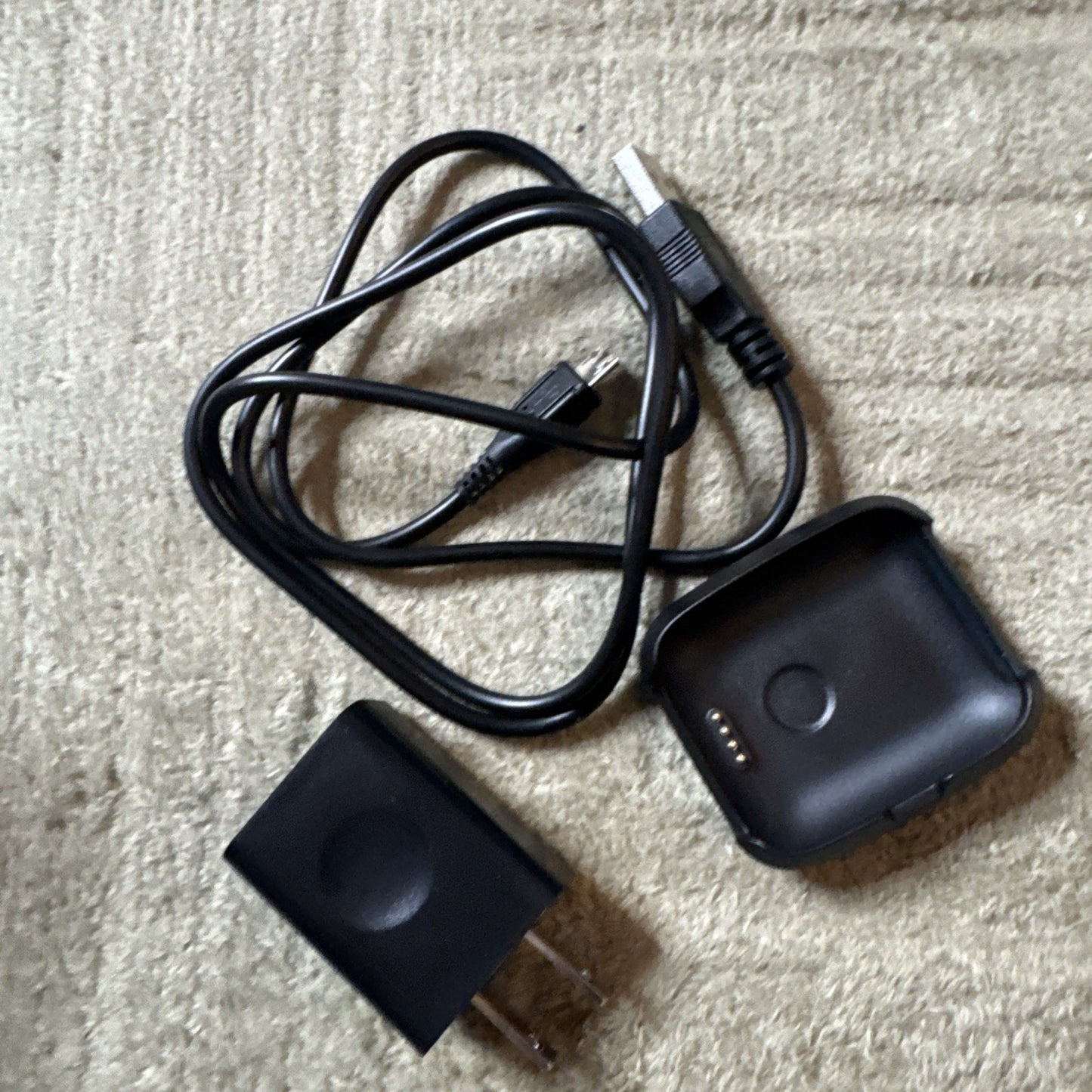 Bit Smart Watch Model S1 charging dock with USB cable and black power adapter on beige surface
