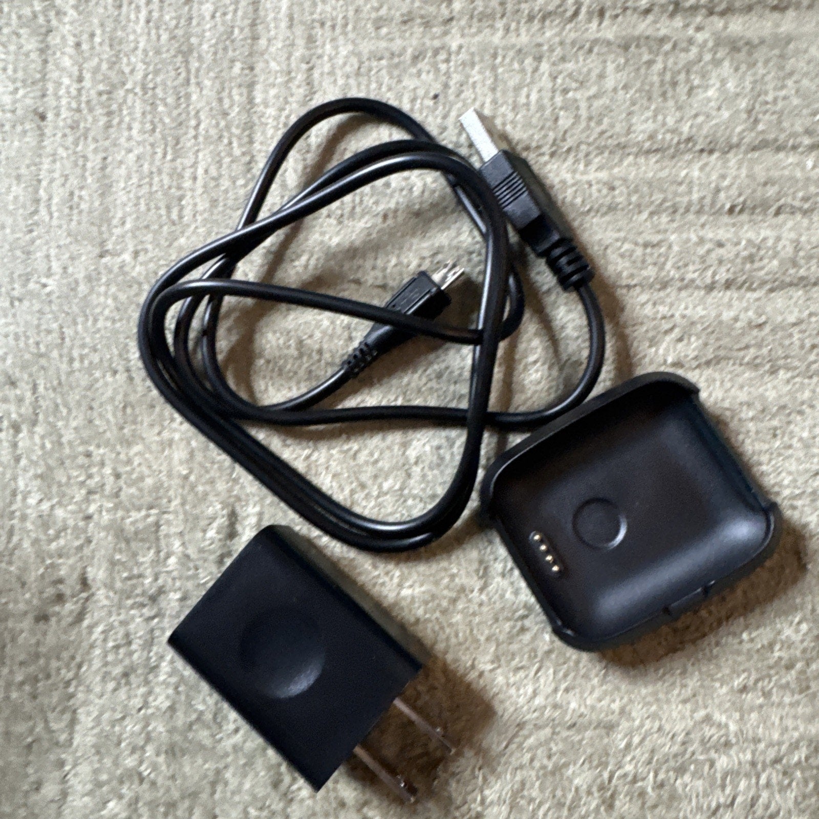 Bit Smart Watch Model S1 charging dock with USB cable and black power adapter on beige surface