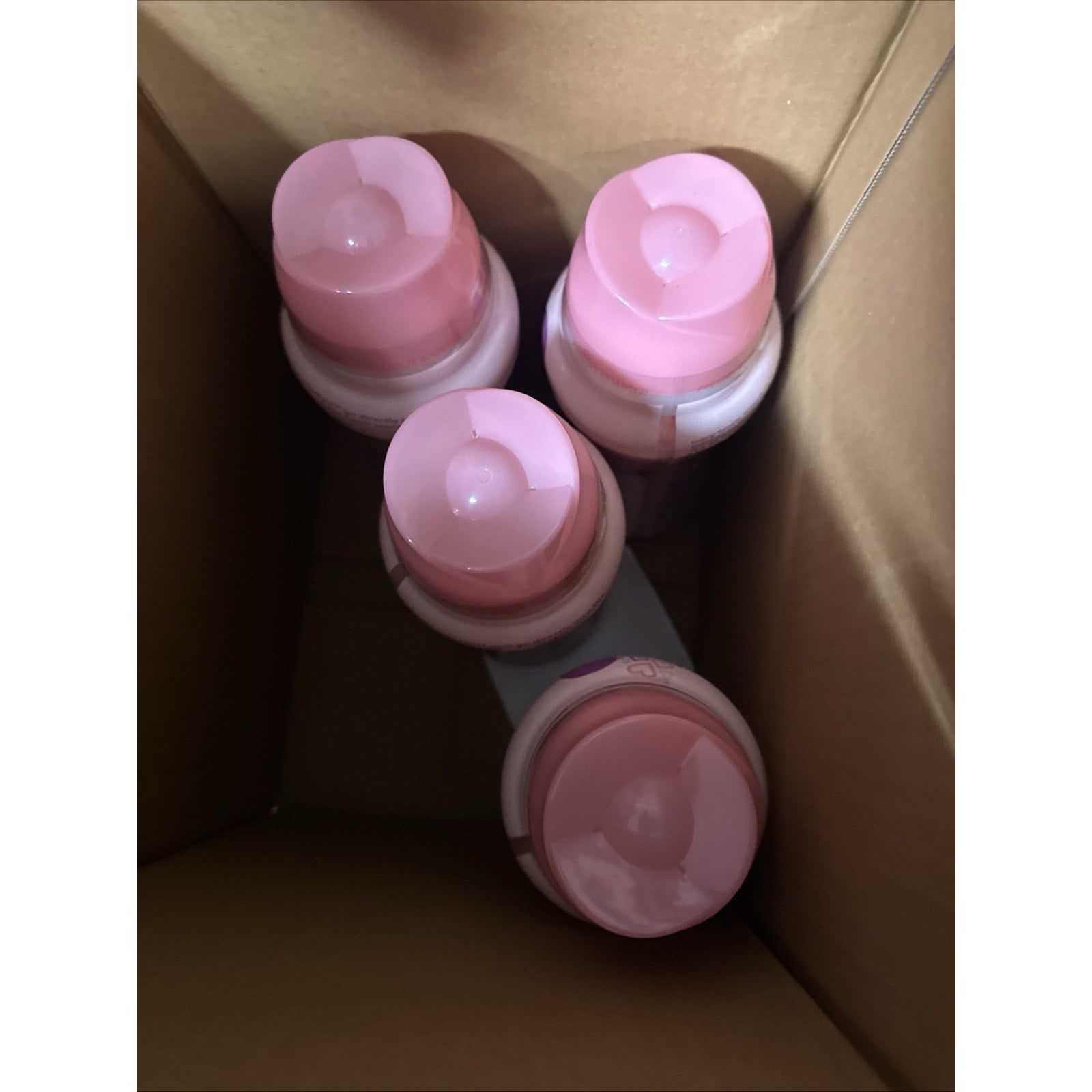 Four bottles of Ivory Snow Blissfuls In-Wash Laundry Scent Booster Beads with pink caps inside a cardboard box