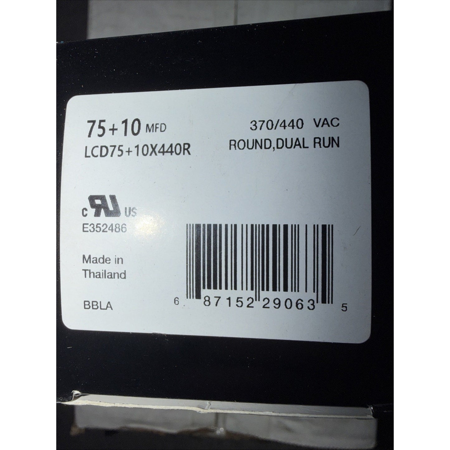 White product label on black surface showing electrical specifications including "75+10 MFD," "370/440 VAC," model number "LCD75+10X440R," certification marks, barcode, and "Made in Thailand" text.