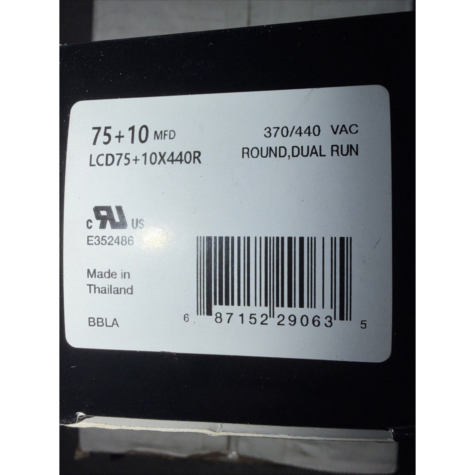 White product label on black surface showing electrical specifications including "75+10 MFD," "370/440 VAC," model number "LCD75+10X440R," certification marks, barcode, and "Made in Thailand" text.