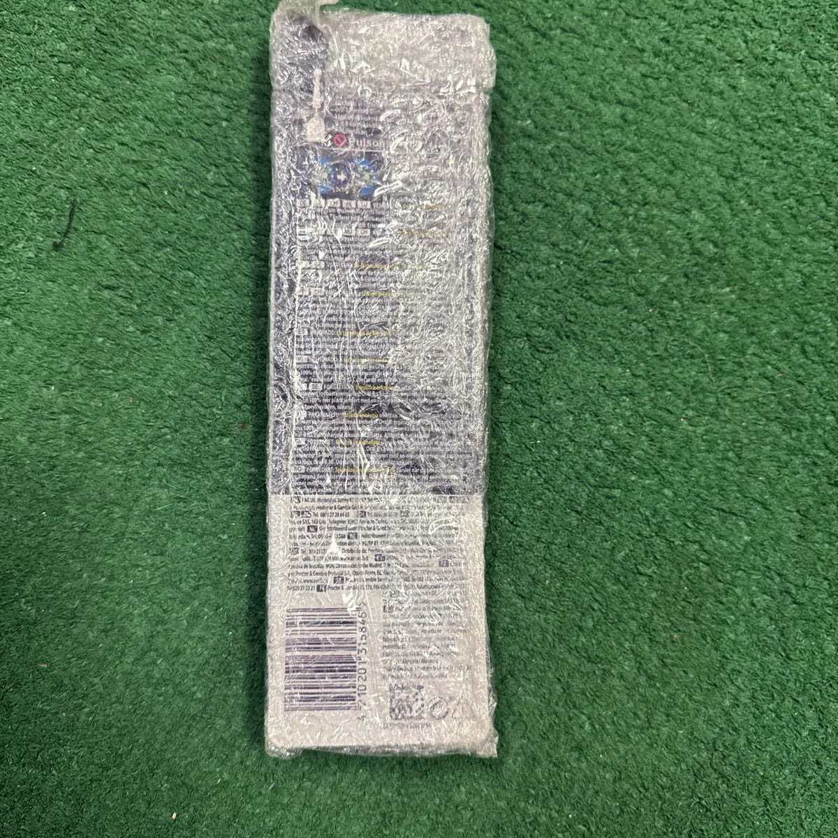Oral B Cross Action Brush Heads 4-pack wrapped in protective bubble wrap on green surface showing product back details