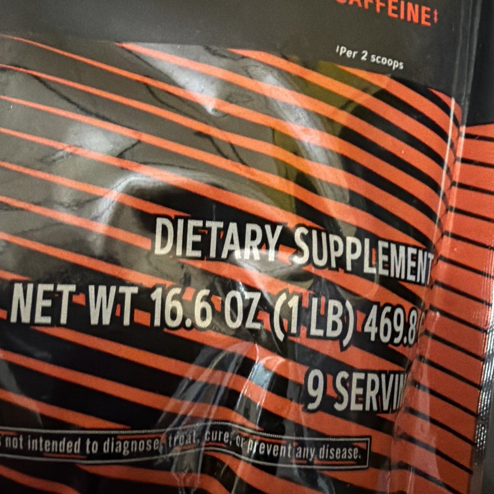 Close-up of black and orange striped dietary supplement package showing net weight of 16.6 ounces (1 pound) and 9 servings per container.