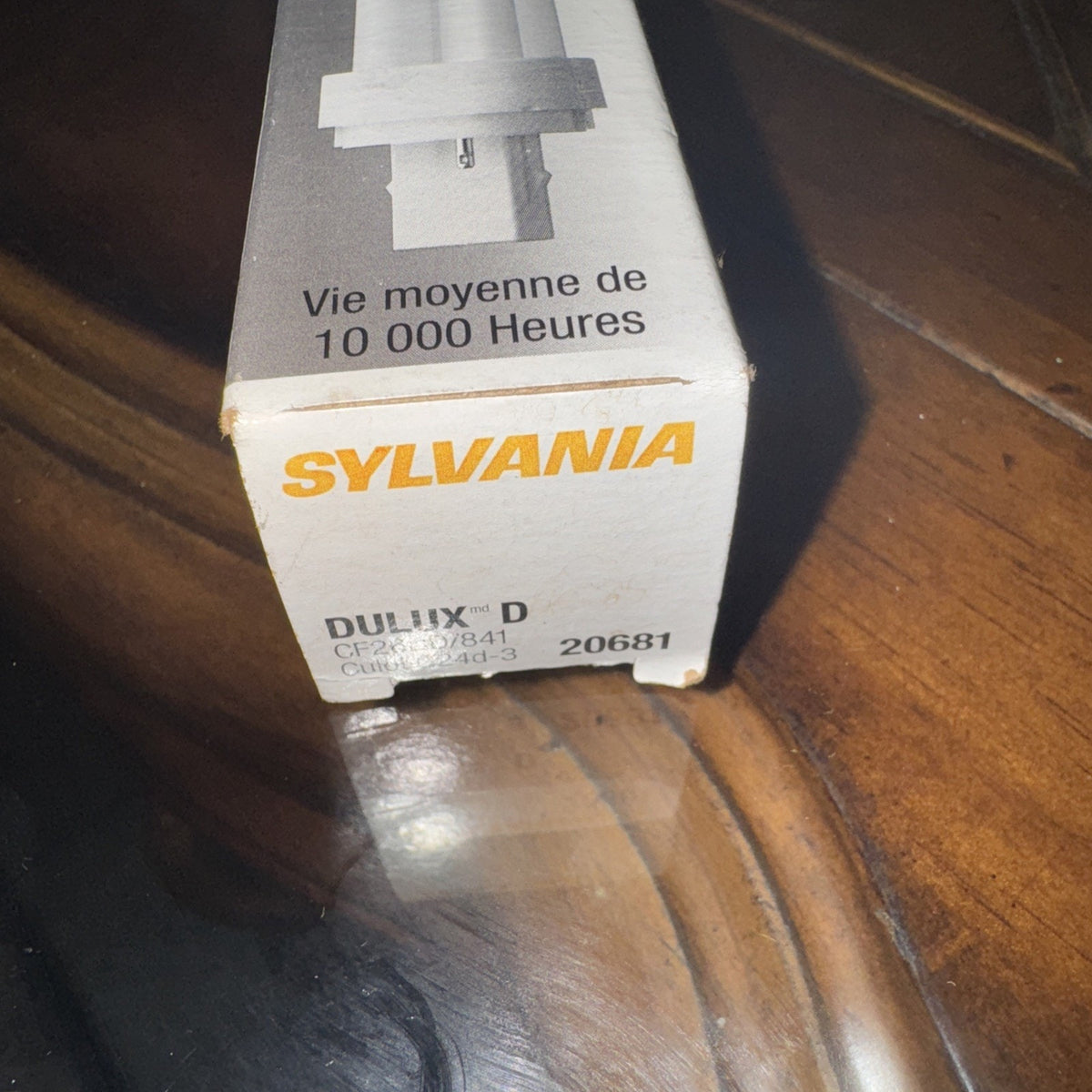 Sylvania 26W 4100K G24D-3 compact fluorescent light bulb box showing brand and product details on wooden surface