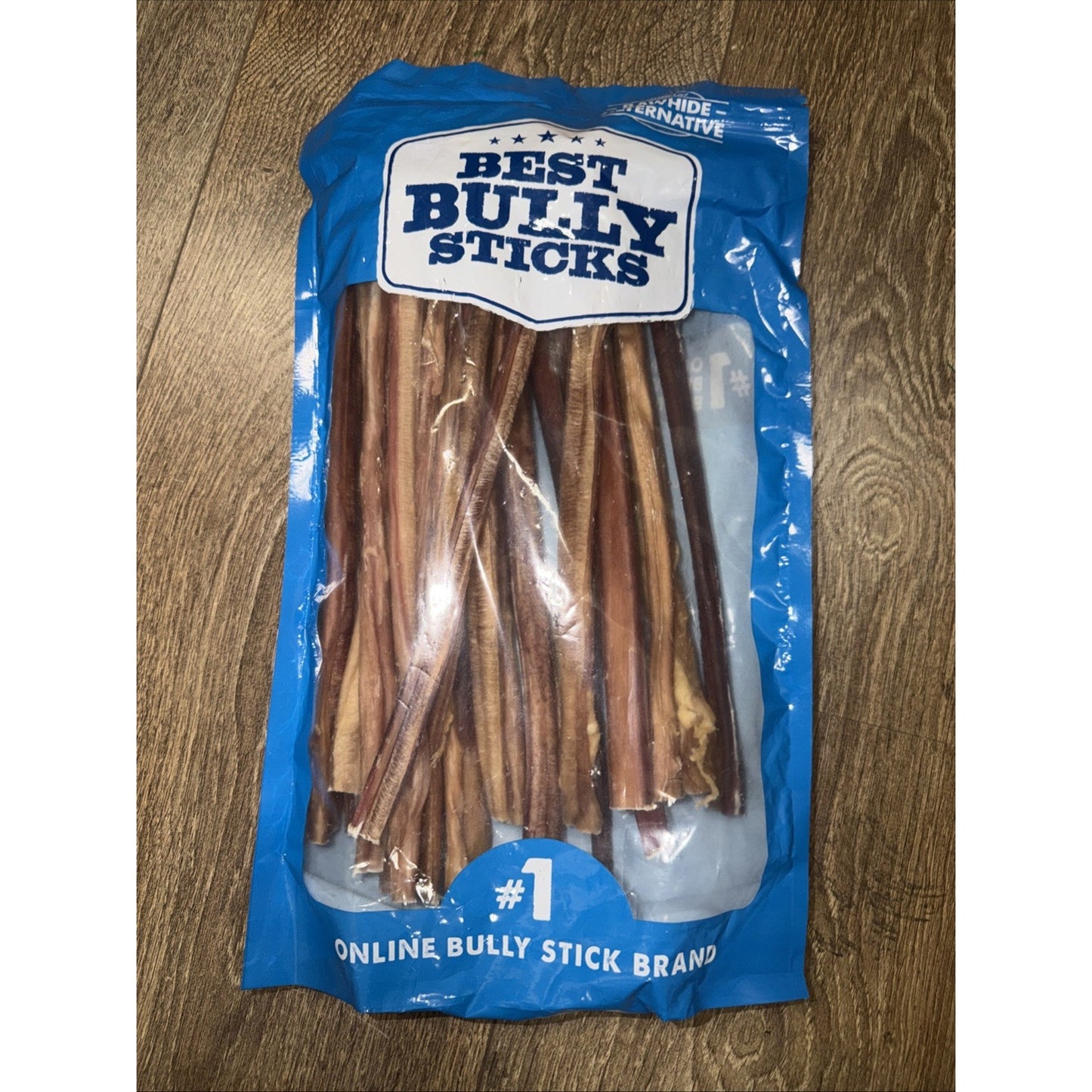Blue resealable bag containing several natural brown bully sticks for dogs, labeled with "Best Bully Sticks" and "#1 Online Bully Stick Brand" on a wooden surface.