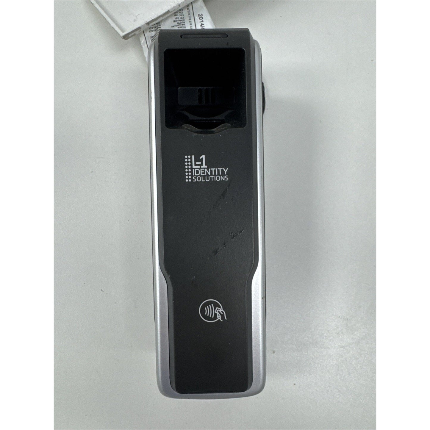 Portable black and silver electronic device with a fingerprint scanner and contactless payment symbol, branded with "L1 Identity Solutions" on a white surface.
