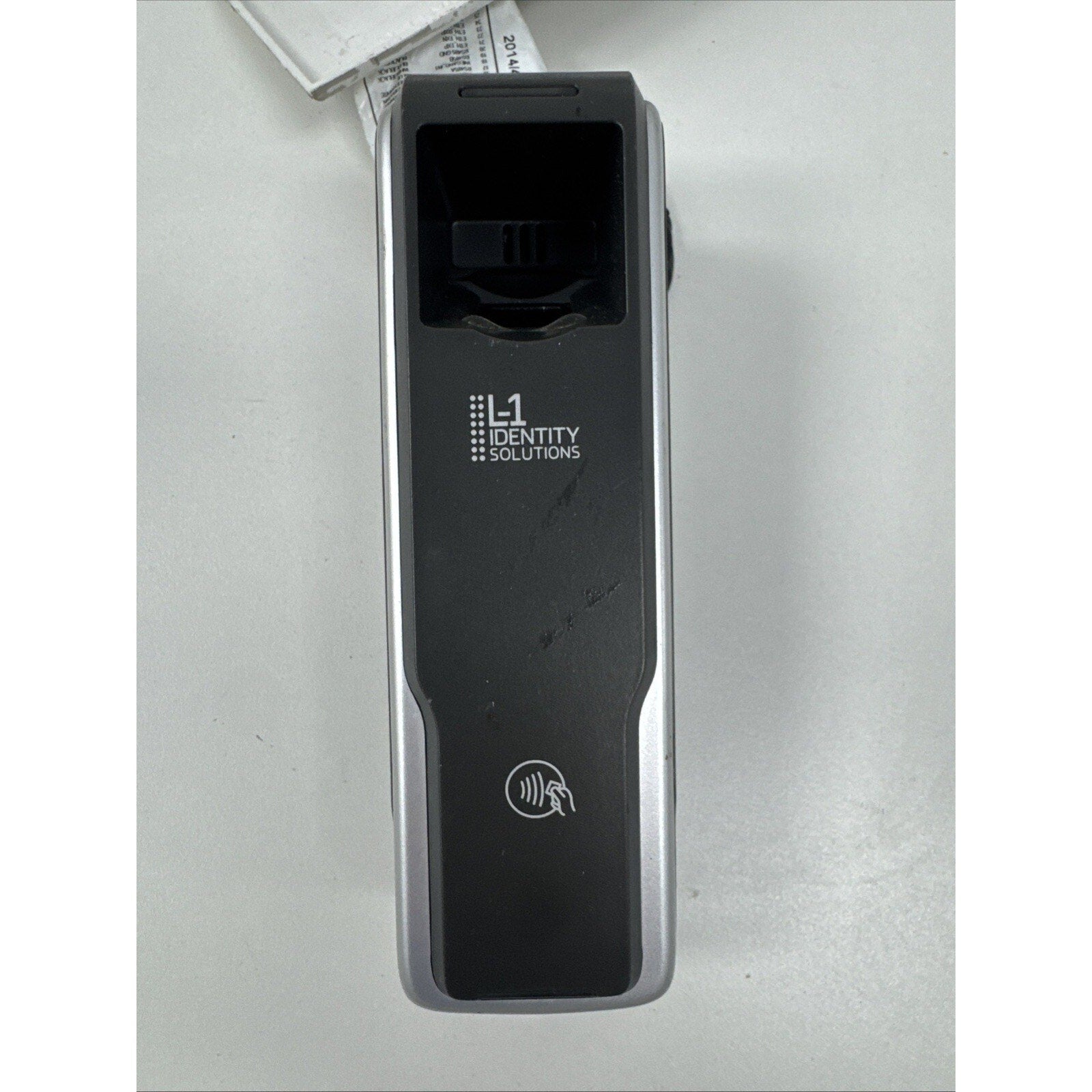 Portable black and silver electronic device with a fingerprint scanner and contactless payment symbol, branded with "L1 Identity Solutions" on a white surface.