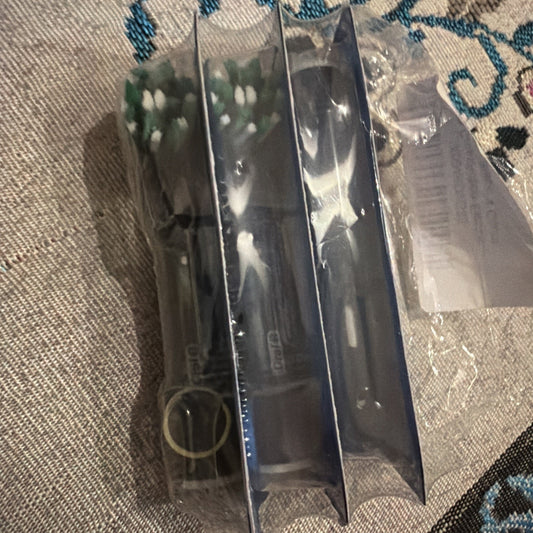 Three-pack Oral B Cross Action black replacement electric toothbrush heads in sealed plastic packaging