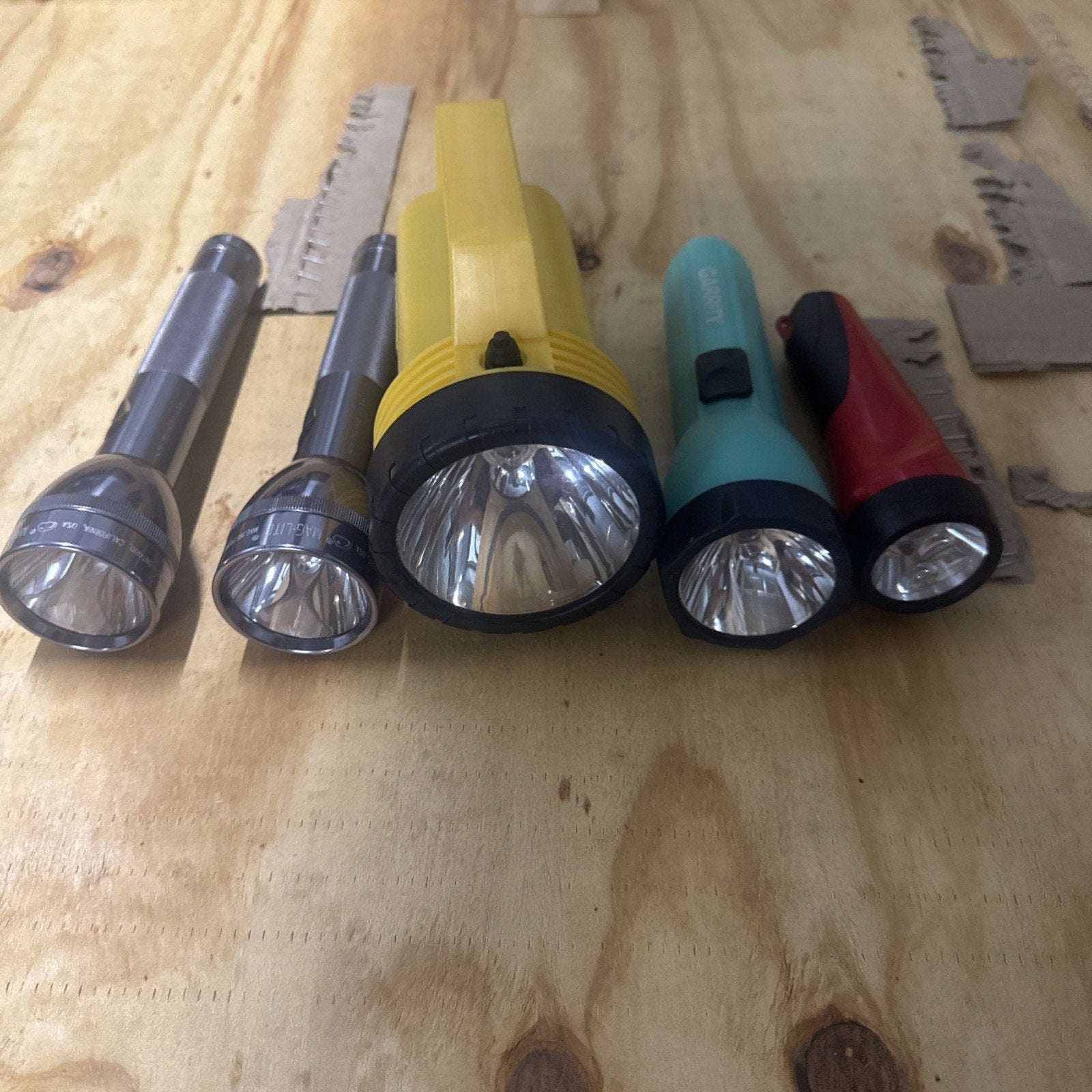 Lot of 5 vintage working flashlights including yellow Maglite style and Eveready Garrity models on wood surface