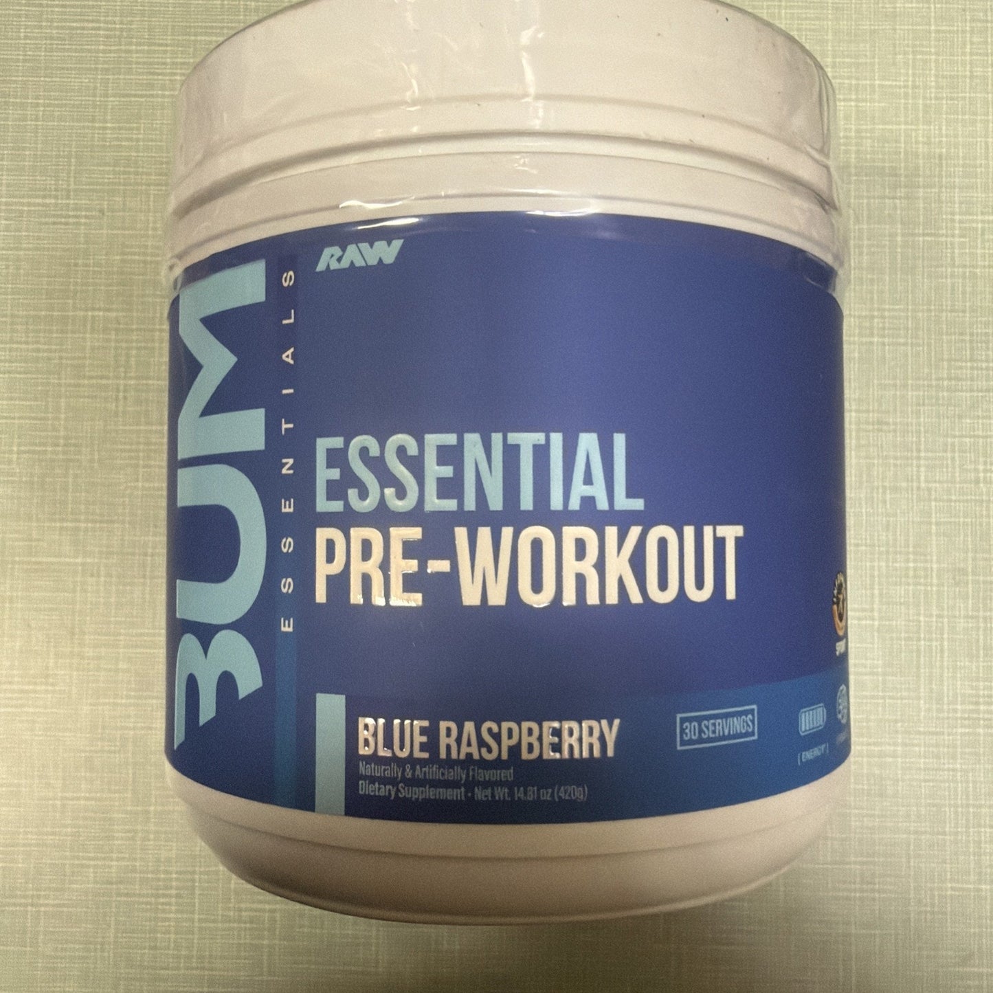 White plastic container of RAW BUM Essential Pre-Workout supplement in Blue Raspberry flavor with a blue label and white and light blue text, offering 30 servings.