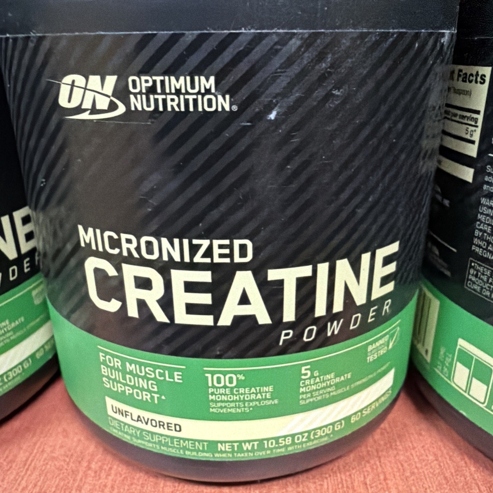 Black and green container of Optimum Nutrition Micronized Creatine Powder labeled unflavored with 5 grams of pure creatine monohydrate per serving and net weight of 300 grams.