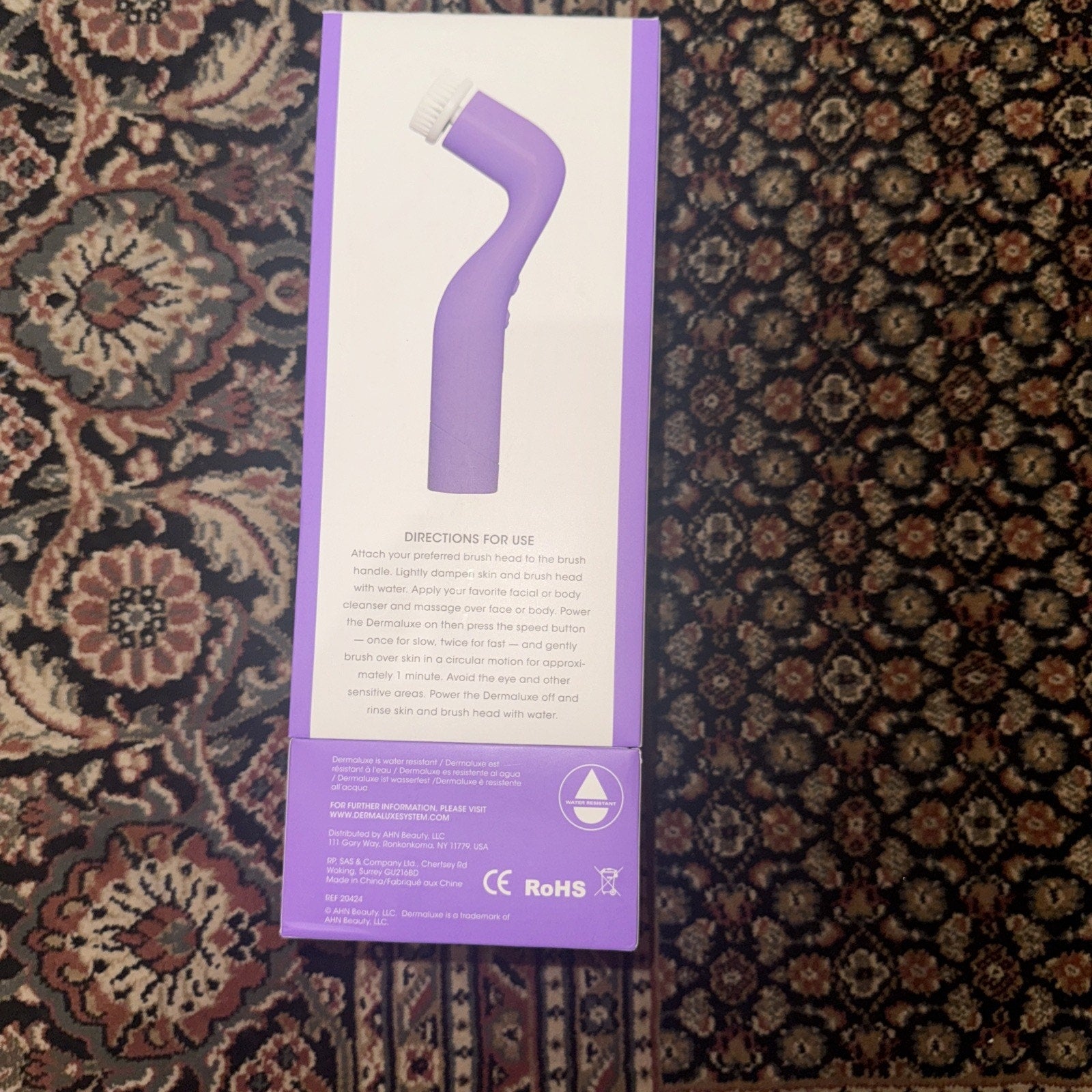 Dermaluxe Advance Cleansing System in purple with two speeds and four brush heads shown on product box back view