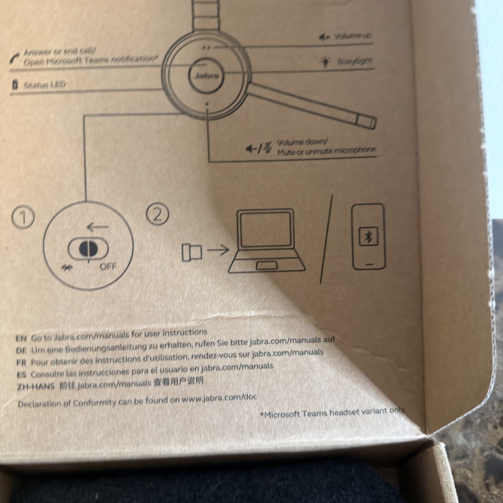Inside of a brown cardboard box featuring printed setup instructions and illustrated diagrams for connecting a Jabra wireless headset via Bluetooth to a computer or mobile device.
