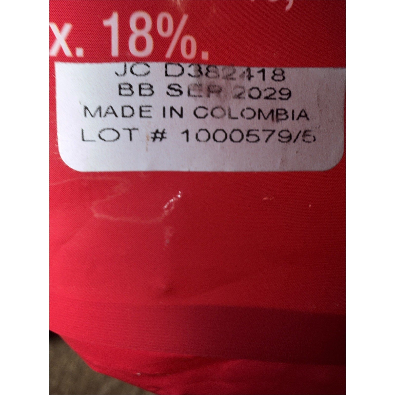 Close-up of a white label on red packaging showing batch number, best before date of September 2029, and "Made in Colombia" text.