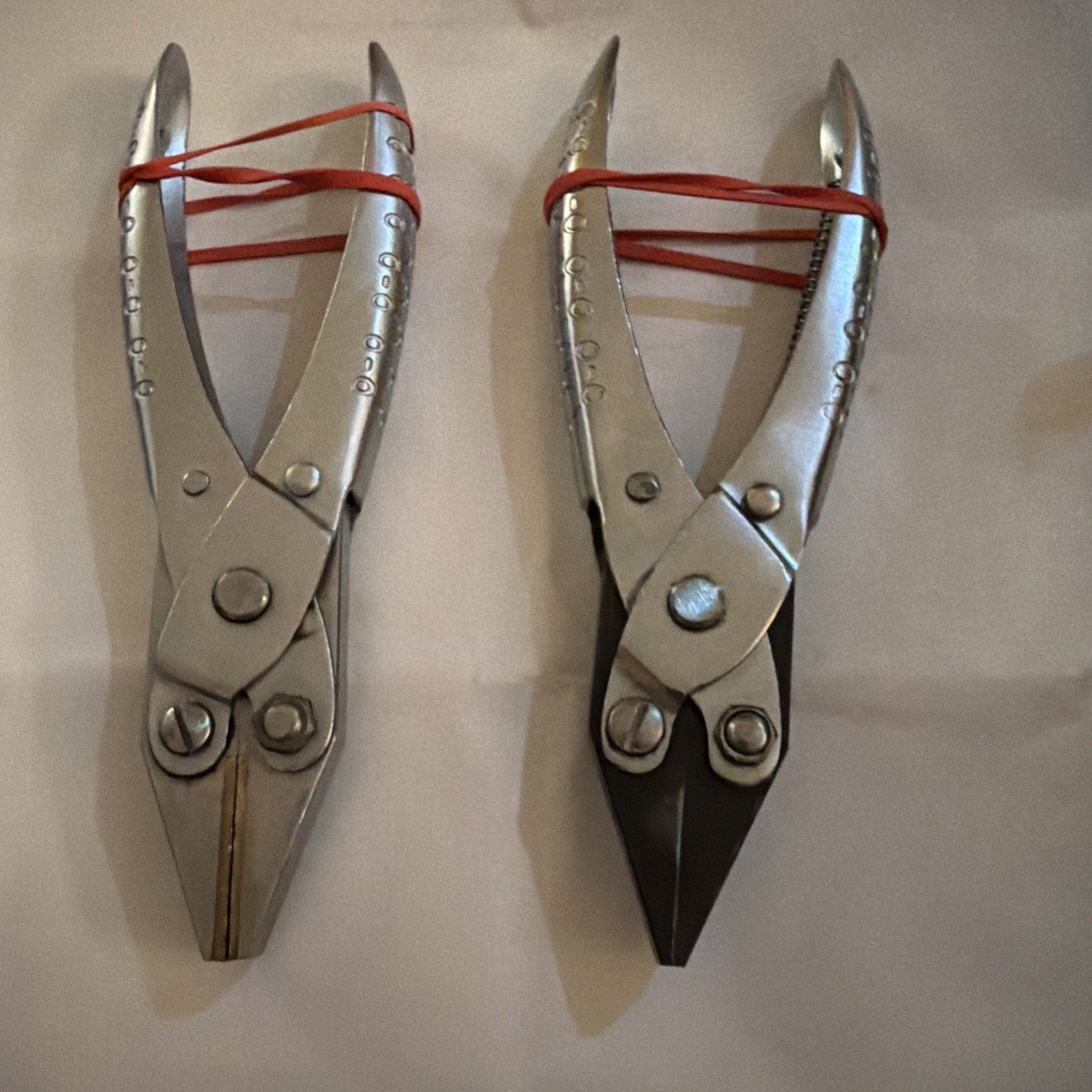 Pair of Aviation Snips Sheet Metal Shears with left cut and straight cut blades secured by red bands on white background