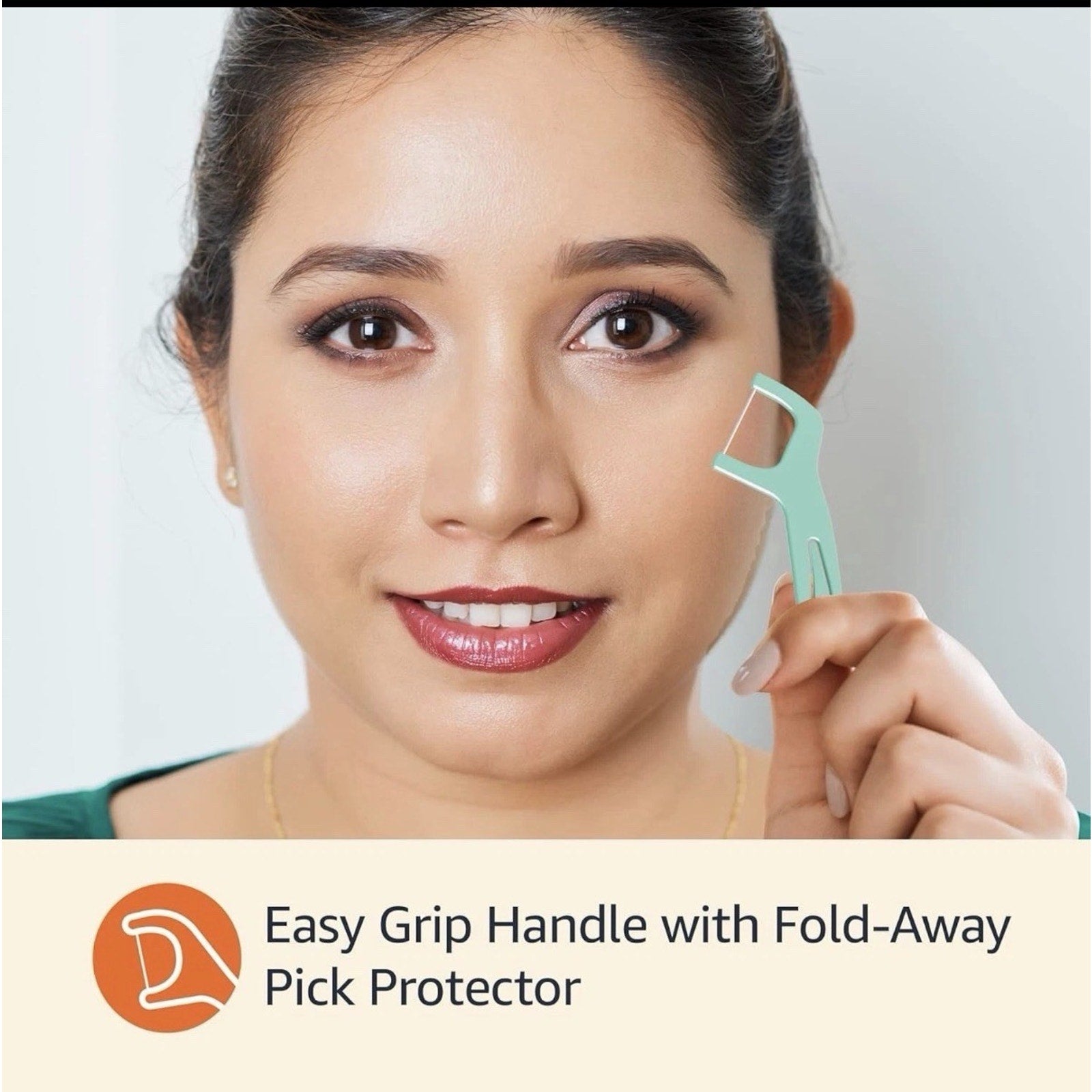 Woman holding mint green dental flosser with easy grip handle and fold-away pick protector close to face