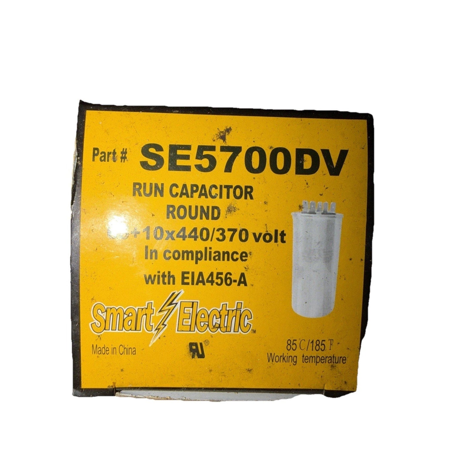 Yellow product label for a round run capacitor with part number SE5700DV, showing specifications of 10x440/370 volts, compliance with EIA456-A, and a working temperature of 85°C/185°F, made in China.