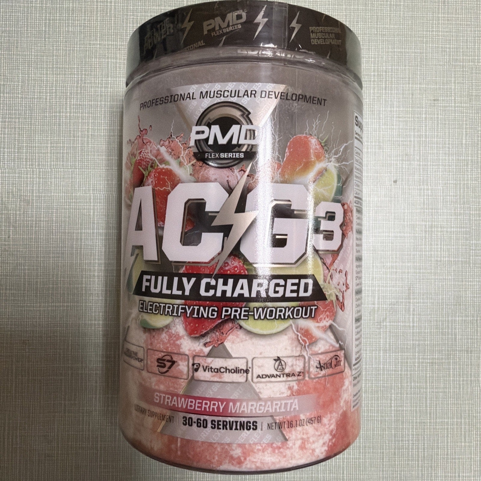 Container of PMD ACG3 Fully Charged pre-workout powder in Strawberry Margarita flavor featuring bold electrifying design with images of strawberries and limes on a light textured background.