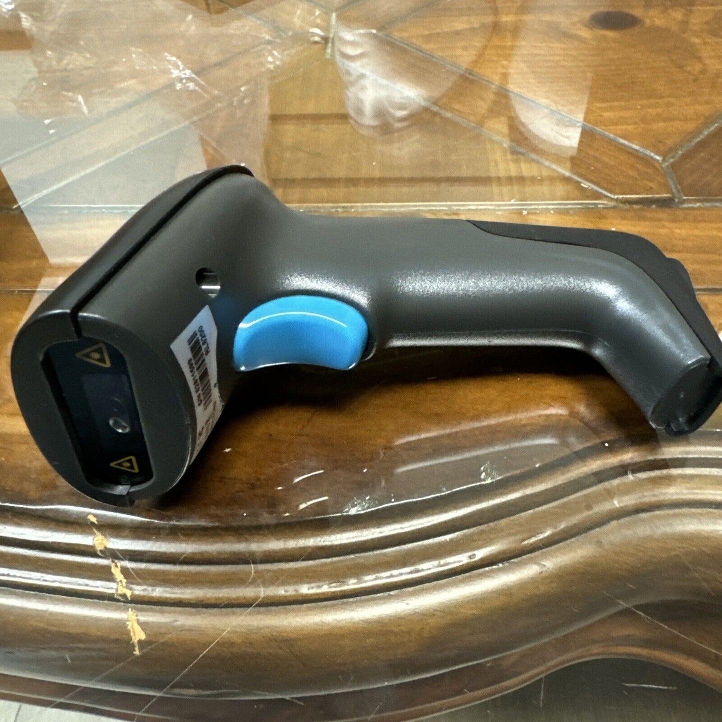 Realinn RL6200 wireless barcode scanner with blue trigger and USB rechargeable 2D QR code scanner on wooden surface