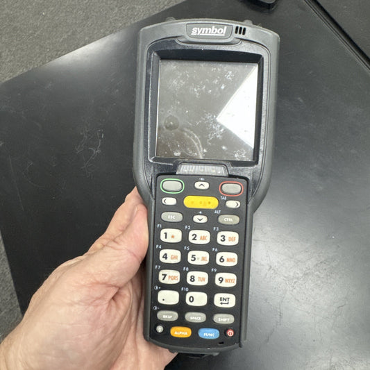 Handheld Motorola Symbol MC3090 mobile barcode scanner with screen and keypad held in hand on black surface