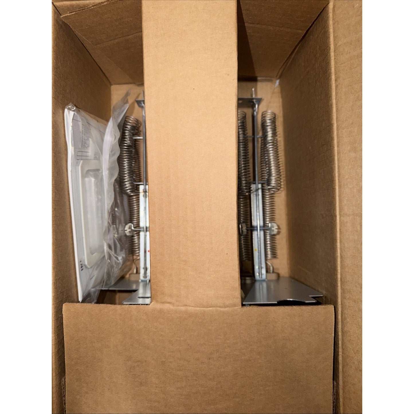 Brown cardboard box containing metal mounting brackets with attached coiled springs and hardware components, separated by a vertical cardboard divider.