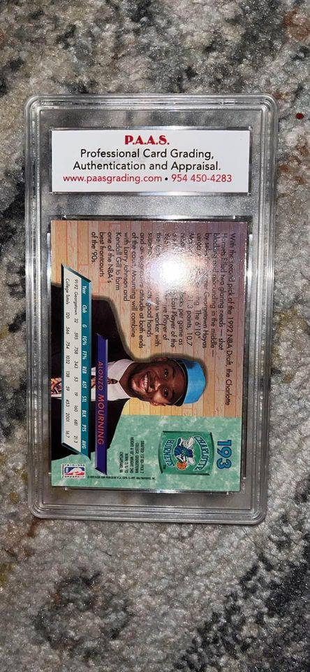 Back of graded Alonzo Mourning basketball card in protective plastic slab on carpet background