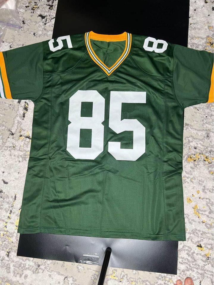 Green football jersey with number 85, signed by Robert Tonyan, displayed on a light carpet background